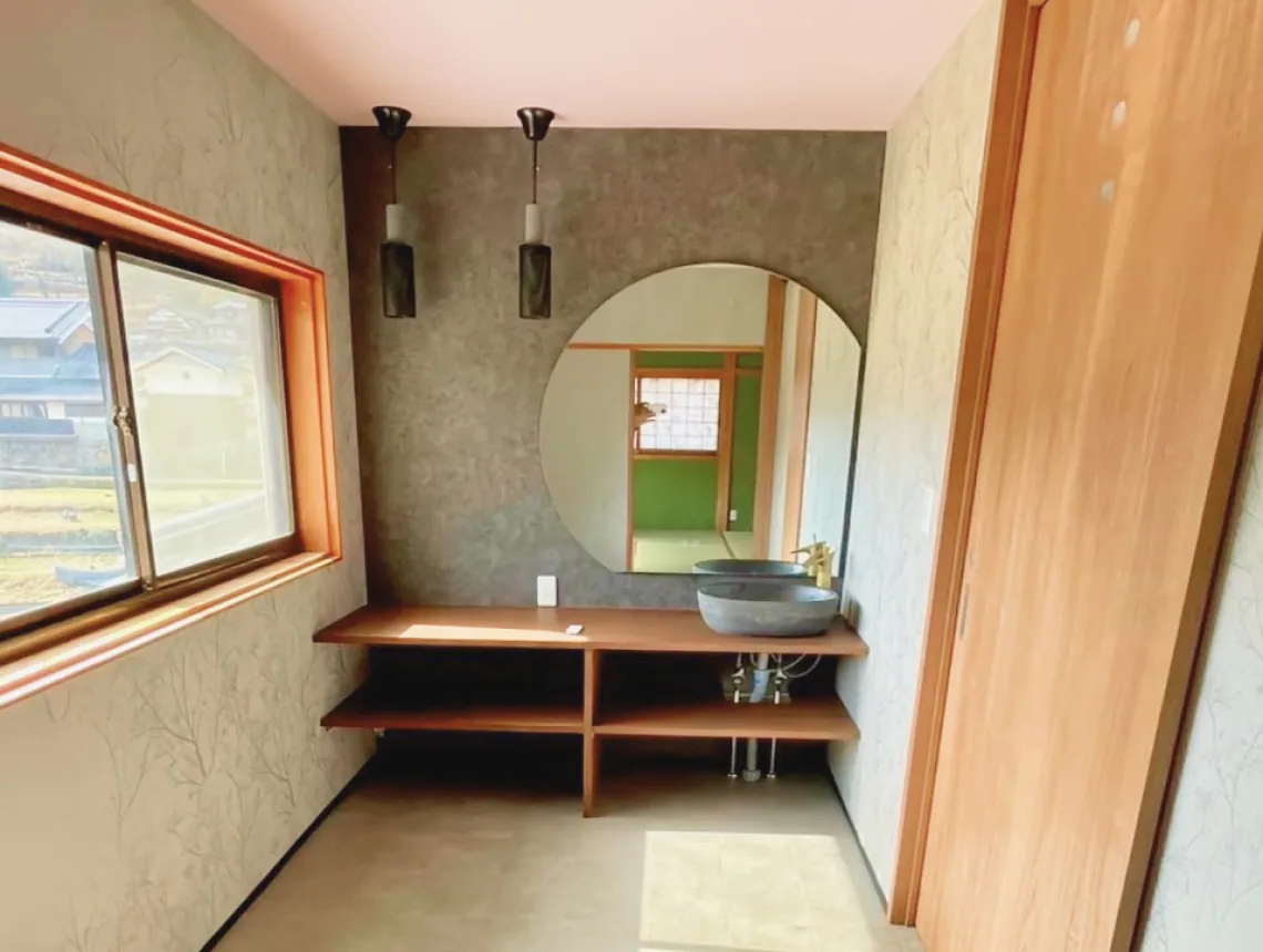 N様邸 空き家を民泊施設へフルリノベーション（宇陀市・補助金200万円活用）— 円形ミラーと和室への抜けが印象的な洗面まわり